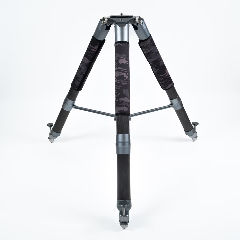 A camera tripod with three legs, featuring black camouflage grips and metallic parts, set against a white background.